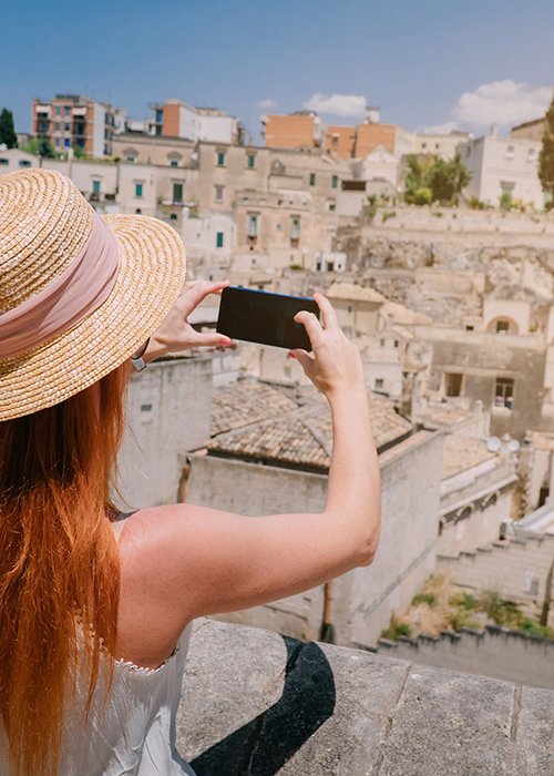 A young woman tourist photographs a panorama of an ancient European city.