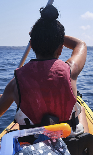 Faceless woman rowing kayak on sea
