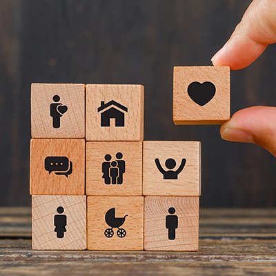 Relationship concept on wooden background side view. hand holding wooden cube with heart icon.