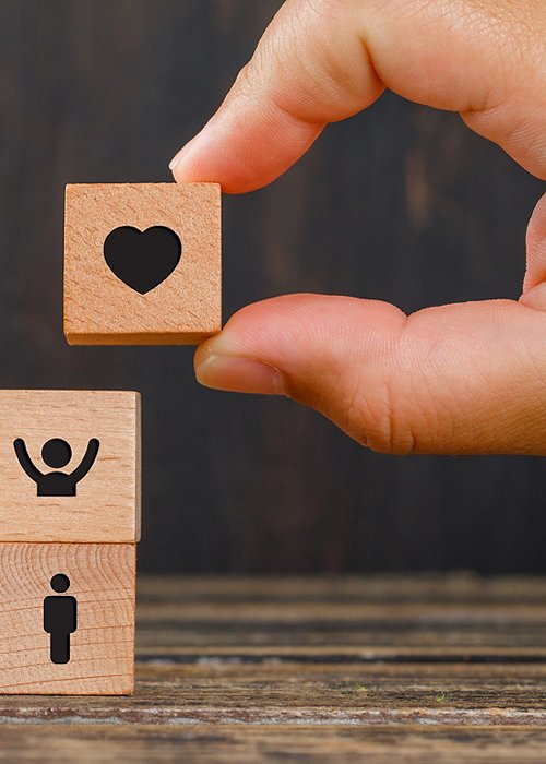 Relationship concept on wooden background side view. hand holding wooden cube with heart icon.