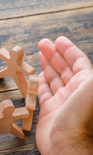 Business success concept on wooden background high angle view. hands protecting wooden figures of people.