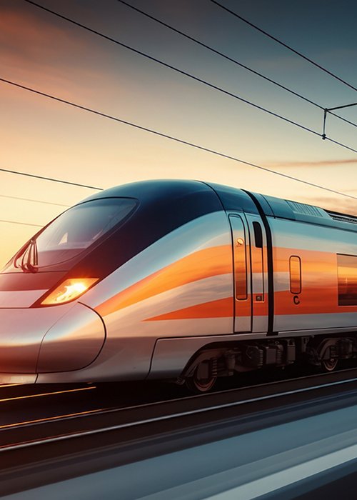 A high-speed train blurring past on tracks at sunset.