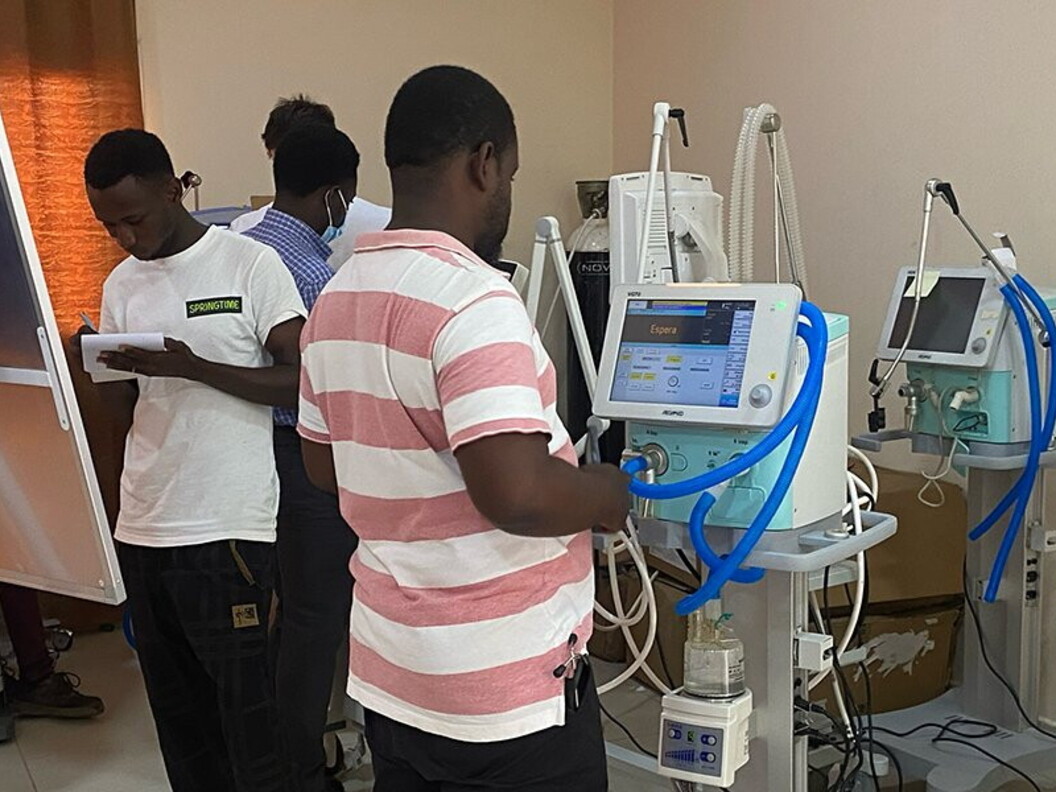 A group of people are focused on the operation of a monitor